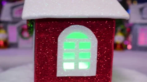 A red house rotates on a lighted stand against of a decorated Christmas town Stock Footage 318518058
