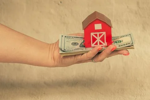 Red house with a stack of dollar bills. The concept of buying a house. Foto stock