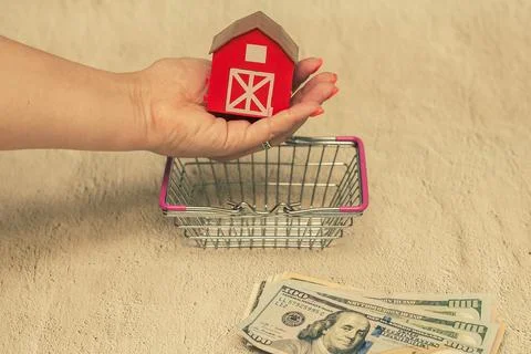 Red house with a stack of dollar bills. The concept of buying a house. Stock Photos