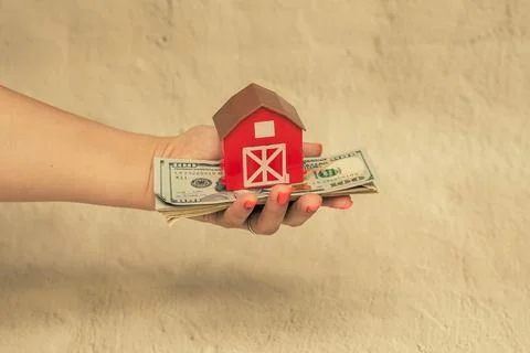 Red house with a stack of dollar bills. The concept of buying a house. Stock Photos