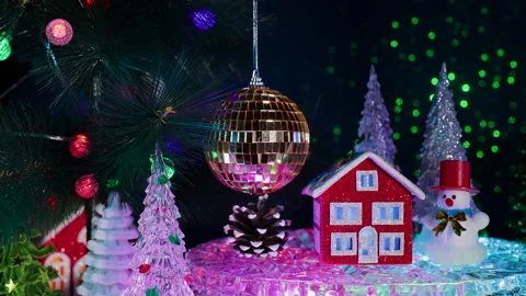A red house surrounded by a snowman and fir trees near a hanging Christmas ball Stock Footage 326850053