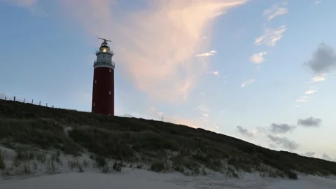 Red iconic lighthouse on small hill. Red lighthouse after sunset with lights on. Stock Footage 220521022