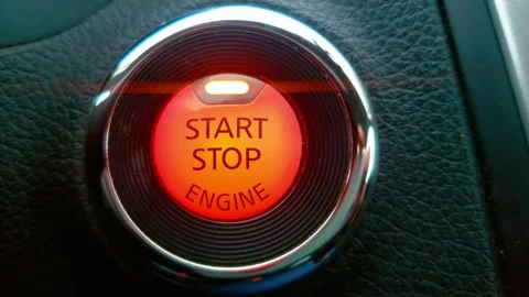 Red illuminated car engine start-stop button on a textured dashboard Stock Footage 324617052