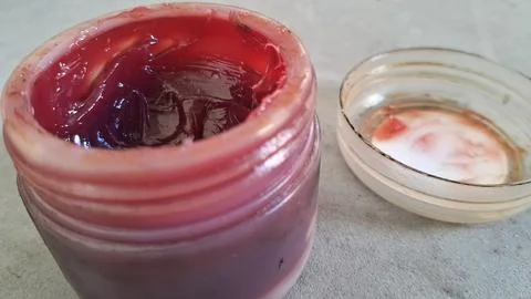 Red industrial grease inside a small open plastic glass jar Stock Photos