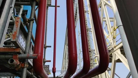 Red Industrial Pipes in Structural Framework Against Sky Stock Photos