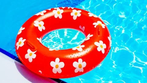 Red inflatable ring with a daisy pattern in the pool Stock Photos