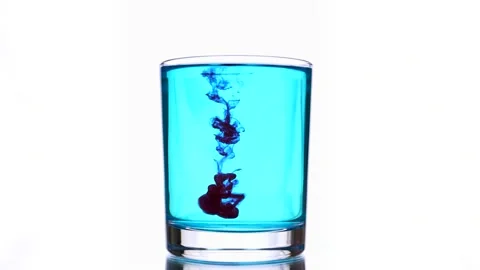 Red ink drops fall into a glass with light blue water. Stock Footage 154438207