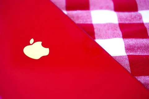 Red iPhone on a red and white chequered blanket with the Apple logo visible Stock Photos
