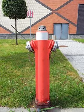 Red iron pole fire hydrant on the background of green grass Stock Photos