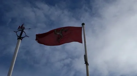 Red Isle of Man flag waving in the wind, manx, blue sky with white clouds Stock Footage 43172391