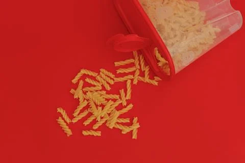 Red jar with macaroni on red background, monochrome Stock Photos