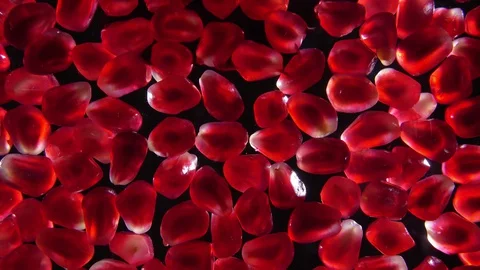 Red juice flows on shining pomegranate grains laying on the black background Stock Footage 129117601