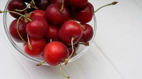 Red juicy and large cherries in a glass bowl on a white table Stock Photos