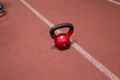 Red kettlebell on athletic track with soft ambient lighting, highlighting t.. Stock Photos