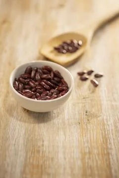 Red kidney beans in a white ceramic bowl and on a wooden spoon Foto stock