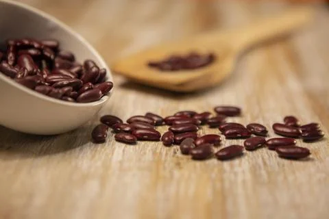 Red kidney beans in a white ceramic bowl and on a wooden spoon Foto stock