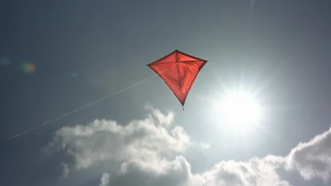 Red kite flying into the sky with clouds and sunflares | Color Corrected Stock Footage 124584218