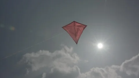 Red kite flying into the sky with clouds and sunflares | LOG Stock Footage 124585686