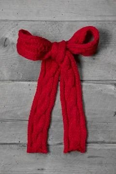 Red knitted bow for a present on grey wooden background - greeting card for c Stock Photos