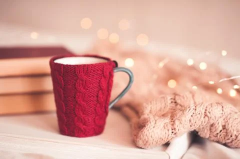 Red knitted cup of coffee with stack of book and knitted scarf over Christmas 스톡 사진