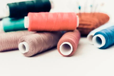 Red knitted needle pad for sewing and colored thread coils on white backgroun Stock Photos