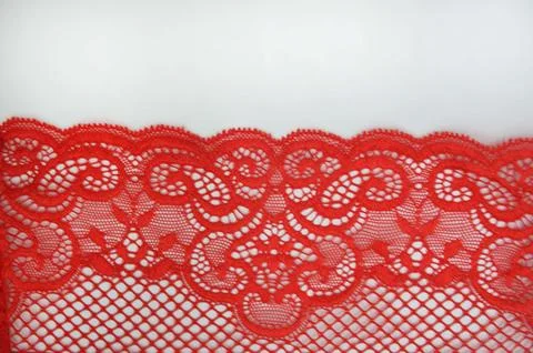 Red lace with a textured openwork pattern on a white background. An element.. Foto stock