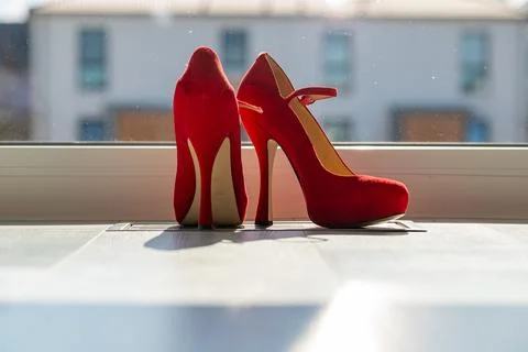 Red ladies pumps on the floor in front of a window Stock Photos