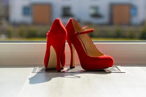 Red ladies pumps on the floor in front of a window Stock Photos