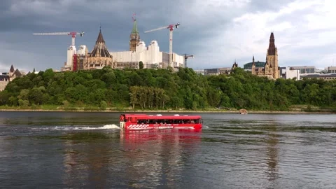 Red Lady Dive tour bus cruising on Ottawa River below Parliament Hill Stock Footage 340912427