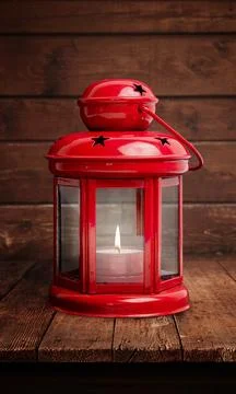 Red lantern with a glowing flame on a rustic wooden table, set against the ag Stock Photos