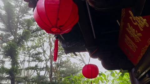 Red Lantern Hanging Under Ornate Wooden Roof With Foggy Forest Behind in Close W Stock Footage 323650300