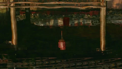 Red lantern reflection shimmers on water with wooden beams above in outdoor Vídeos de archivo 336654776
