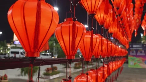 Red lanterns dangling, casting warm light along vietnamese street at night Stock Footage 311302681