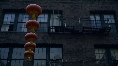 Red Lanterns Vertical String Against Brick Building Low Angle Dusk Video stock 344937901
