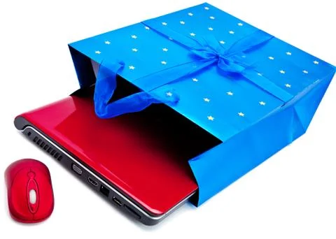 Red laptop and a computer mouse are packed into a gift packet by New year.. Stock Photos