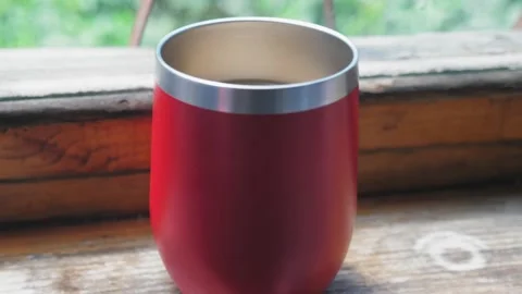 A red large mug with hot coffee stands on a wooden windowsill. The camera flies Stock Footage 198706754