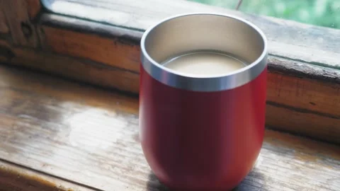 A red large mug with hot coffee stands on a wooden windowsill. The camera flies Stock Footage 199226147
