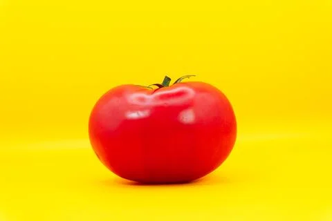 Red large tomato on a yellow background, healthy eating from fruits and Stock Photos