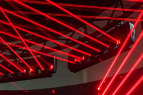 Red laser beams intersecting in a geometric pattern against a dark backdrop B Stock Photos