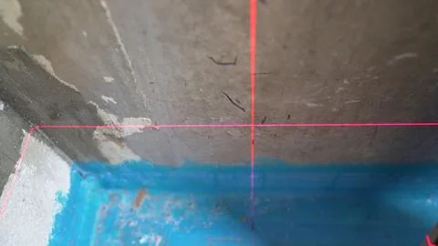 Red laser level crosshair projecting on a rough concrete ceiling during hom.. Stock Photos