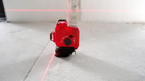 Red laser level projecting cross lines on concrete floor and wall Stock Photos