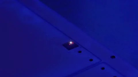 Red laser pointing on electronic device under blue light Stock Footage 316540617