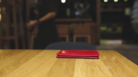 Red leather bill folder lying on brown wooden table in cafe or restaurant. Stock Footage 123344896