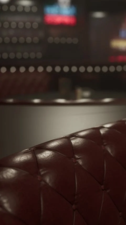 Red leather booth in a dimly lit restaurant with bright screens in background Stock Footage 337963036