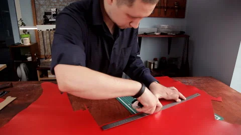 From a red leather layer the man cuts out preparations of skin, using a leather Stock Footage 88841998