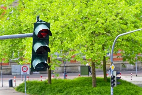 Red left arrow traffic light near zone twenty sign and trees Stock Photos