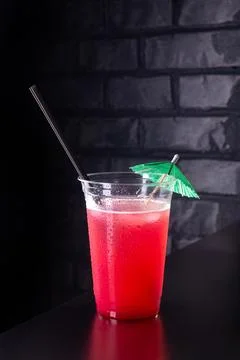 Red lemonade with ice cubes in a plastic glass Stock Photos