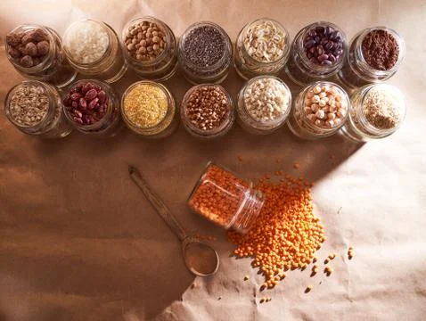 Red lentils close-up. Against the background of a jar with other cereals. Sup Stock Photos