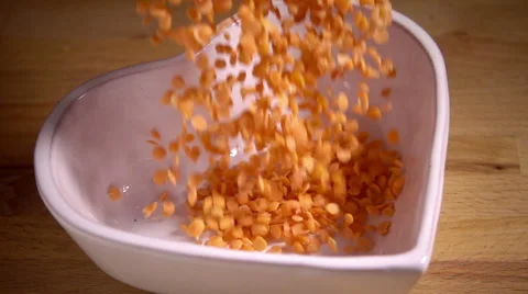 Red lentils falling into heart shaped bowl, slow motion Stock Footage 55452495