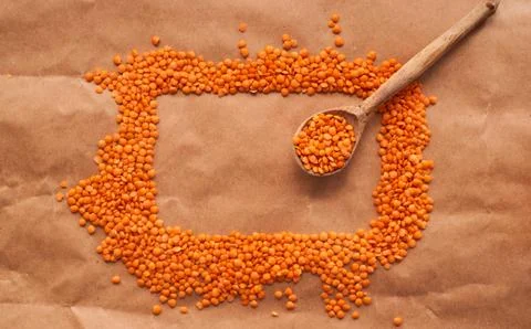 Red lentils lie in the shape of rectangle with wooden spoon on a brown paper  Stock Photos